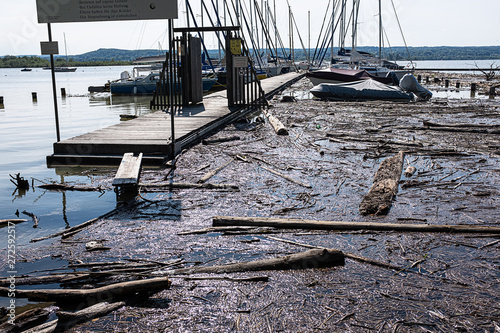 .Boat dock at high water with driftwood and rubbish at lake Ammersee