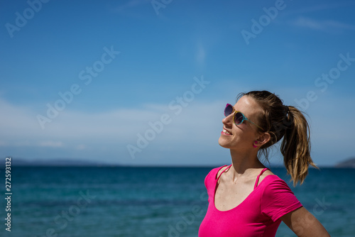 Smiling young woman standing by the sea
