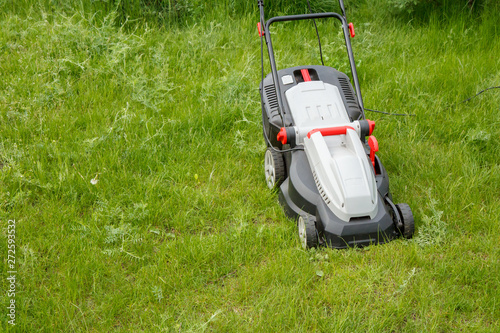 Lawn mower on green grass in the garden