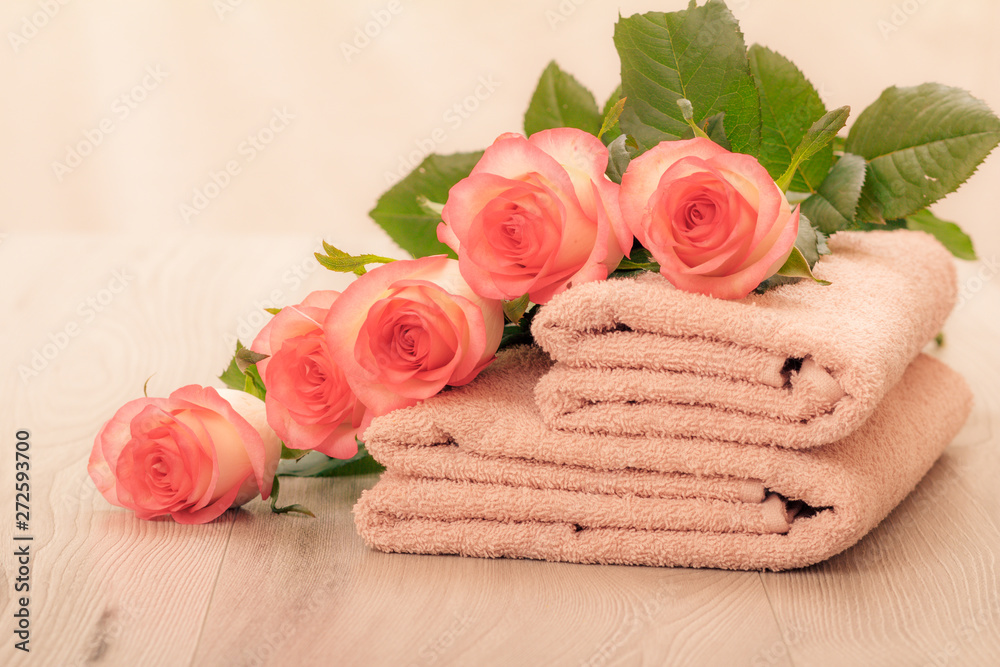 Stack of soft terry towels with flowers on wooden boards Stack of soft terry towels with flowers on wooden boards
