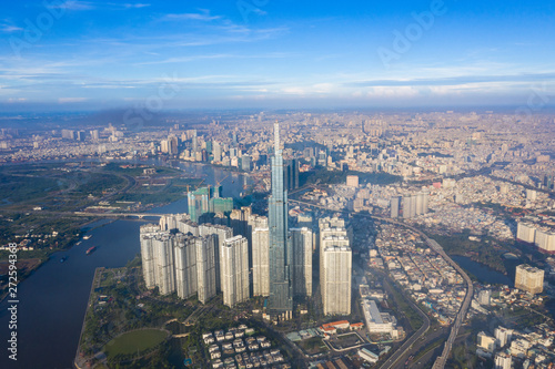 Fototapeta Naklejka Na Ścianę i Meble -  Top View of Building in a City - Aerial view Skyscrapers flying by drone of Ho Chi Mi City with development buildings, transportation, energy power infrastructure. include Landmark 81 and blue sky ,