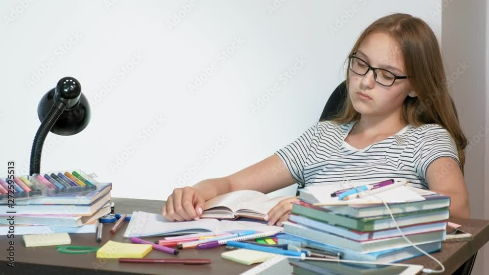 A teenager girl with glasses is sitting at a school desk. learning concept A teenager girl with glasses is sitting at a school desk. learning concept