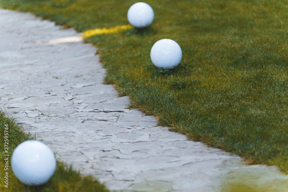 Stone path on a grass field with three garden lamps. Copy space.