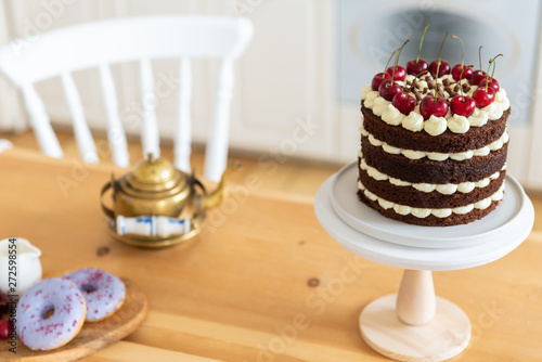 Naked chocolate cake with cherry. Black forest cake, Schwarzwalder Kirschtorte, Schwarzwald pie on the kitchen table. Home made birthday cake. Bakery concept. Copy space photo