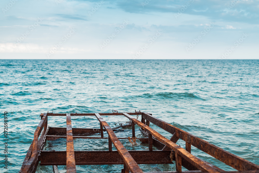 Rusty ruined pier on the sea. Iron structures corroded in water. Rusty ruined pier on the sea. Iron structures corroded in water.