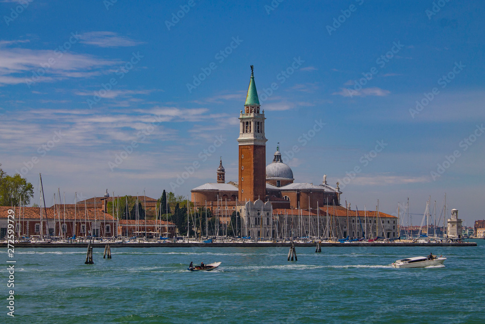 Venice lagoon on a bright summer day. Italy. Landscape with sea boats, colorful houses and an old tower.