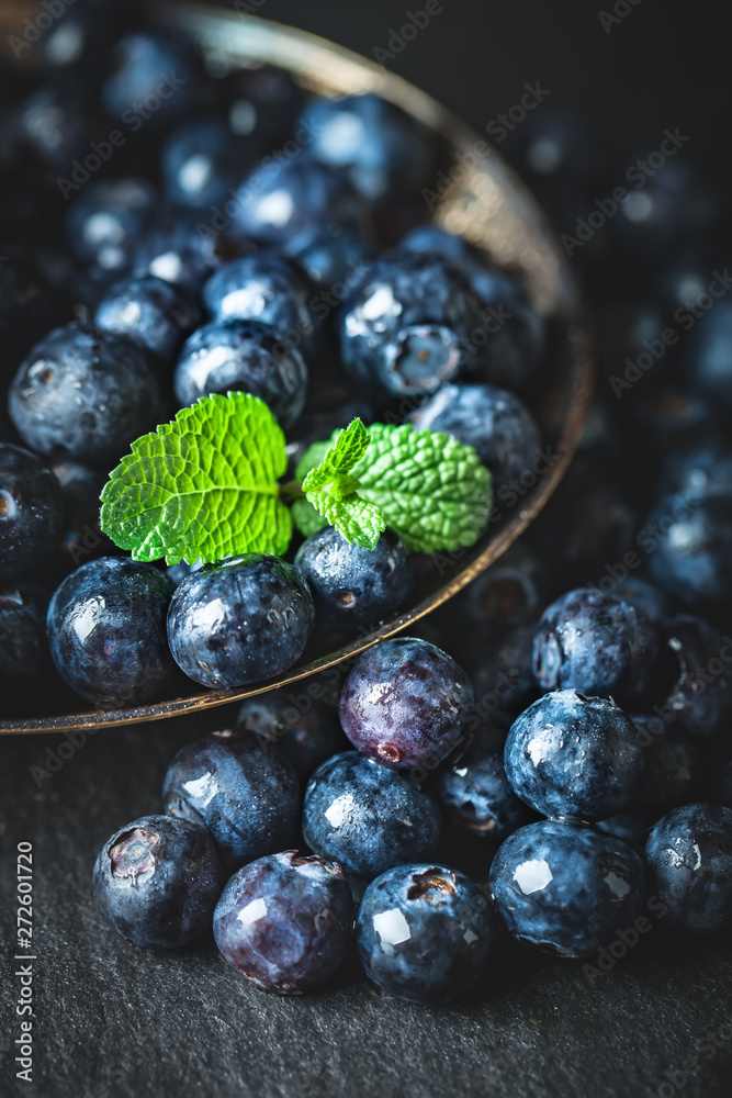 Juicy and fresh blueberries with green leaves on rustic table. Blueberry antioxidant. Concept for healthy eating and nutrition. Selective focus. Juicy and fresh blueberries with green leaves on rustic table. Blueberry antioxidant. Concept for healthy eating and nutrition. Selective focus.