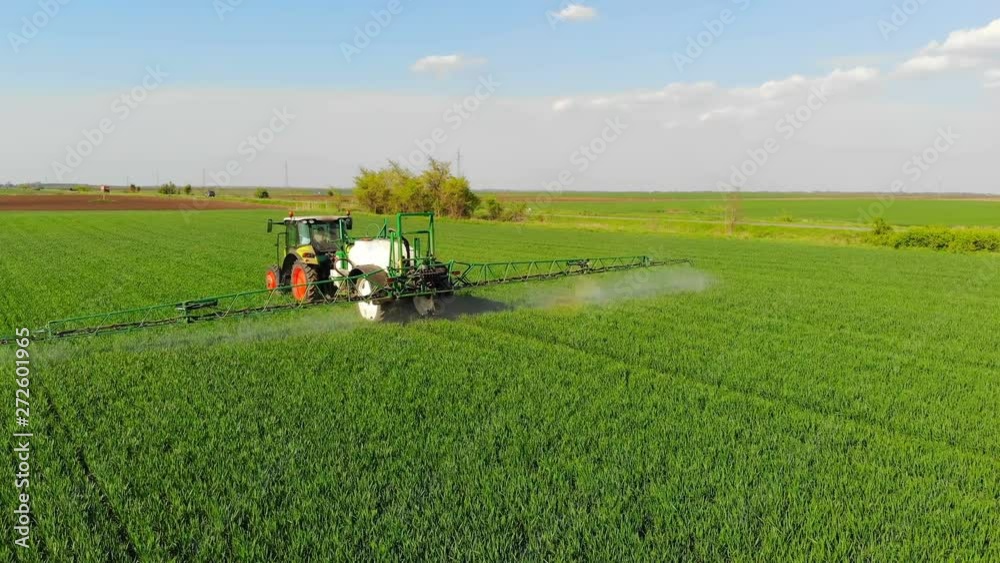 Crop sprayer spraying pesticide on a wheat field. Drone shot flying over agricultural wheat field tractor and crop sprayer, protection plants in order to increase yield Crop sprayer spraying pesticide on a wheat field. Drone shot flying over agricultural wheat field tractor and crop sprayer, protection plants in order to increase yield