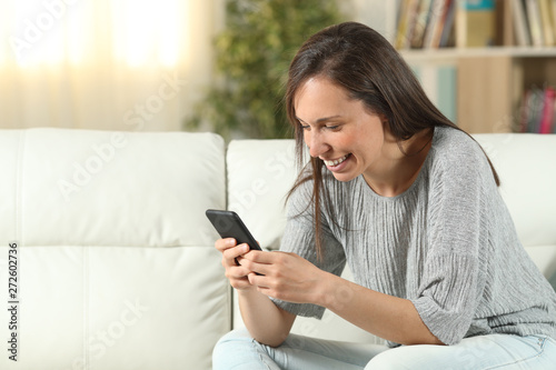 Happy woman at home texting on phone