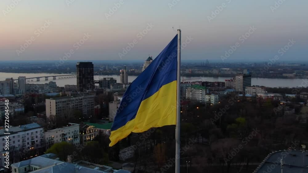 Aerial footage of the flag of Ukraine with the city of Dnipro on the background
