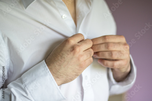 Wedding Groom morning preparations, dress up with white shirt, buttoning up