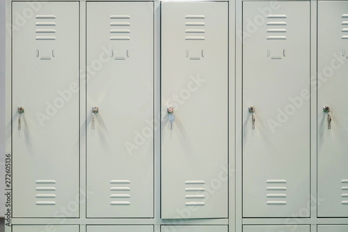A row of grey metal school lockers with keys in the doors photo