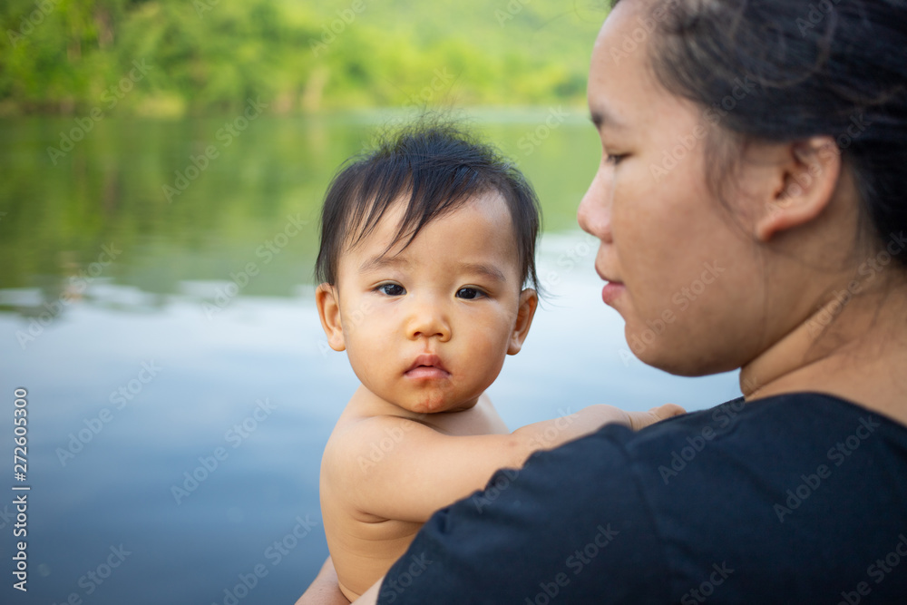 Asian woman carrying baby girl with river background Asian woman carrying baby girl with river background