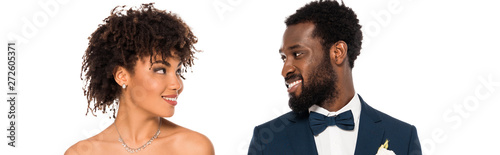 panoramic shot of cheerful african american bride looking at bridegroom isolated on white