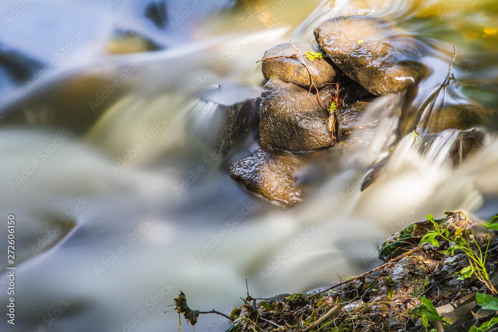 Rapid stream flowing over rocks on a sunny day - long exposure Rapid stream flowing over rocks on a sunny day - long exposure