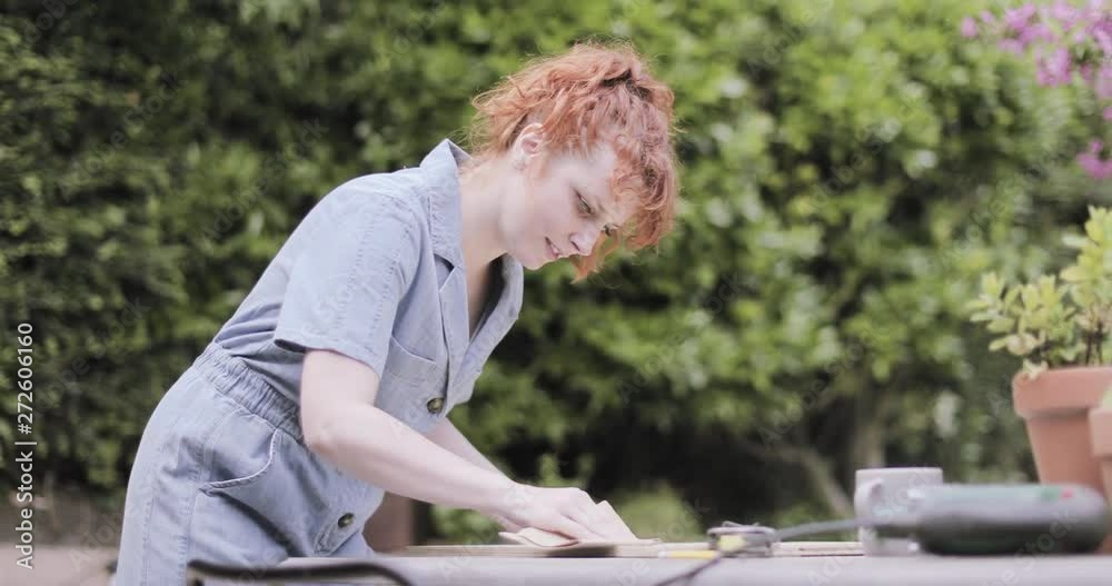 Young Adult woman doing carpentry DIY in garden Young Adult woman doing carpentry DIY in garden