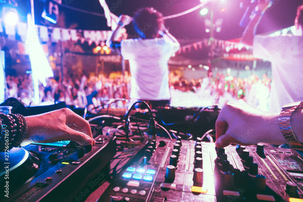 Dj mixing outdoor at beach party festival outdoor with crowd of people in  background - Soft focus on left hand - Fun, summer, youth, nightlife,  music, nightclubs and entertainment concept foto de