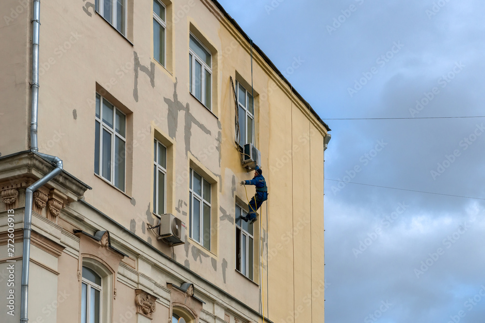 MOSCOW - OCTOBER 27, 2018: A working painter - a mountaineer is painting a residential building