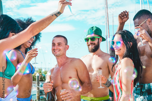 Group of friends drinking champagne in summer boat party - Young people having fun celebrating and cheering - Youth lifestyle, exclusive fest and vacation concept - Main focus on left man face