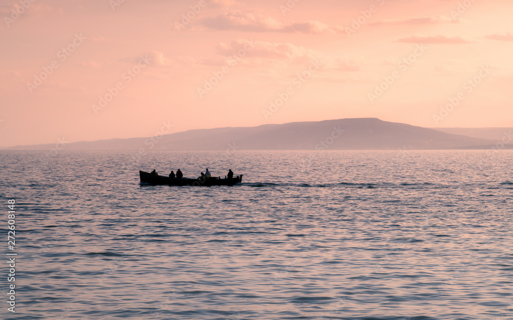 Boat silhouette with man on the water in sunset with mountain in Boat silhouette with man on the water in sunset with mountain in