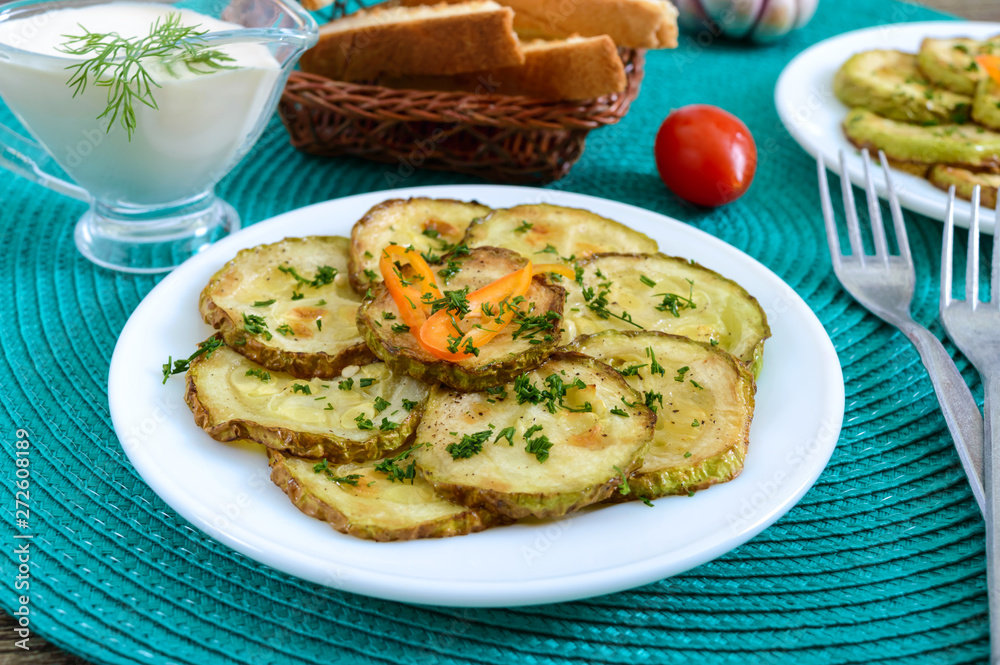 Tasty fried zucchini slices on a plate with sauce on a wooden table. Picnic snack. Rustic style