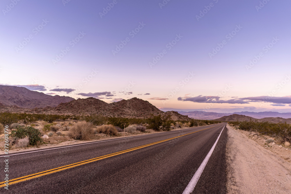 Road side landscape at desert with sunset sky, dry plants and mountains.