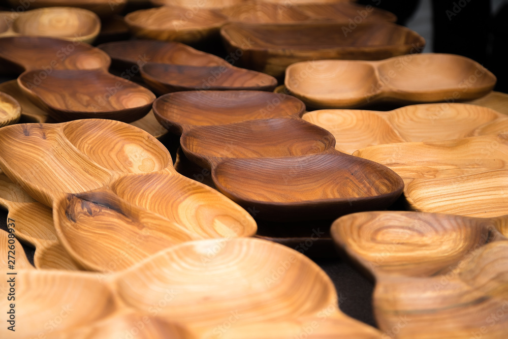 Close up of wooden utensils for the kitchen, bowls, plates on dark background. Concept of natural dishes, a healthy lifestyle. Texture of wood. Wooden eco-ware