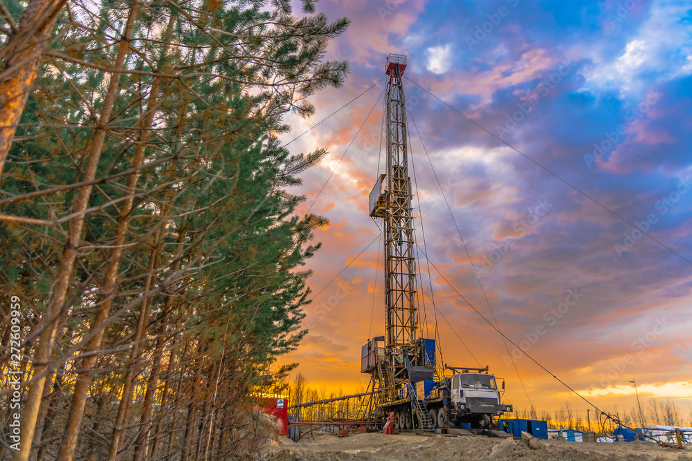 Drilling a deep well mobile drilling rig in an oil and gas field. The field is located in the Far North in the taiga. Beautiful dramatic sunset sky in the background. Drilling a deep well mobile drilling rig in an oil and gas field. The field is located in the Far North in the taiga. Beautiful dramatic sunset sky in the background.