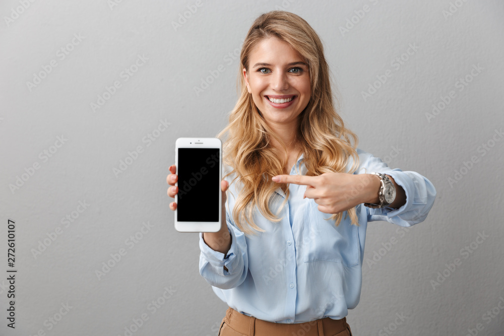 Happy young pretty blonde business woman posing isolated grey wall background showing display of mobile phone. - obrazy, fototapety, plakaty 