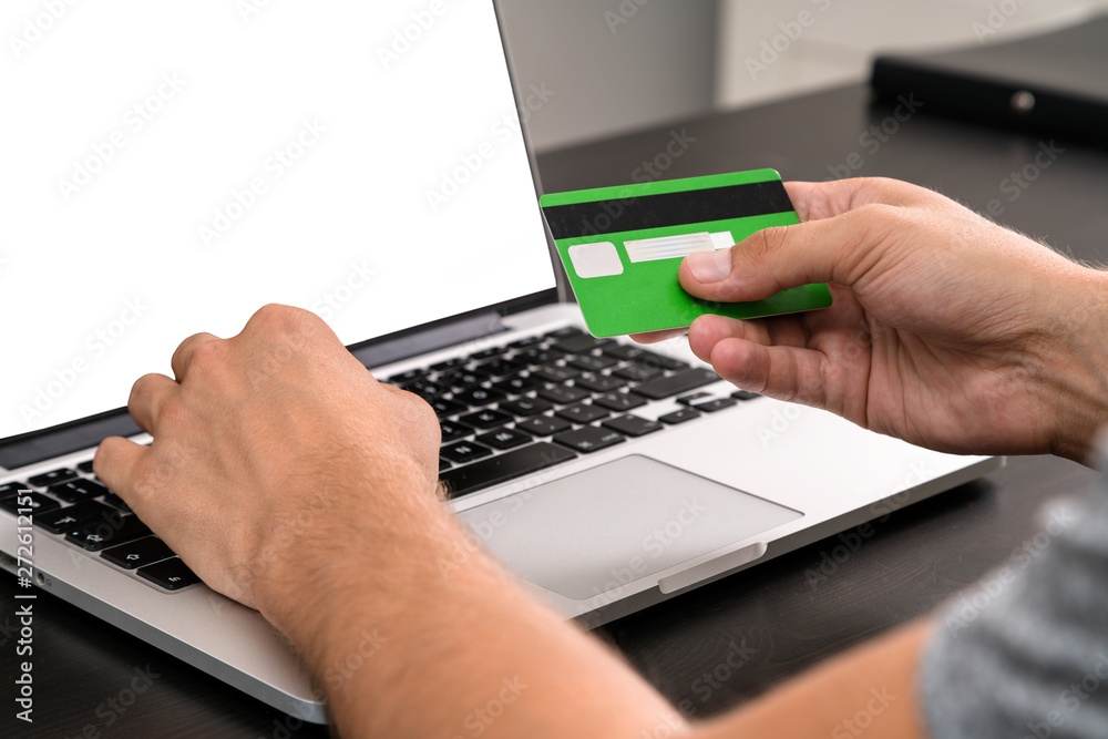 Young business man typing in credit card info on a computer keyb Young business man typing in credit card info on a computer keyb