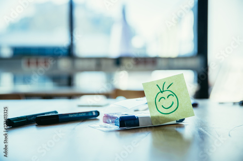 Feedback, motivation and workshop concept: Smiley Illustration on a working place, pens and window in the background