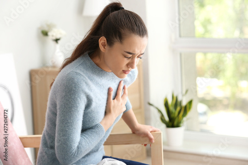 Young woman suffering from heart attack at home