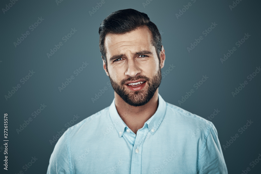 Charming man. Handsome young man looking at camera while standing against grey background Charming man. Handsome young man looking at camera while standing against grey background