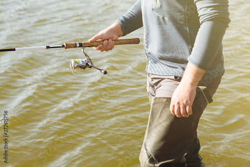 a man in boots standing in the lake and fishing on spinning. Legs close up