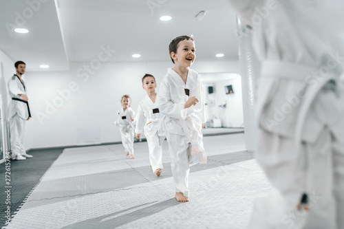 Small group of children having training at taekwondo class. All dressed in doboks. White background.