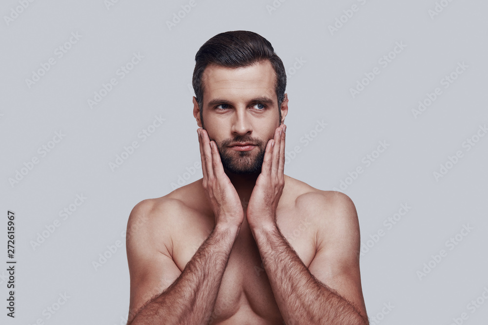 To shave or not to shave? Handsome young man keeping head in hands and