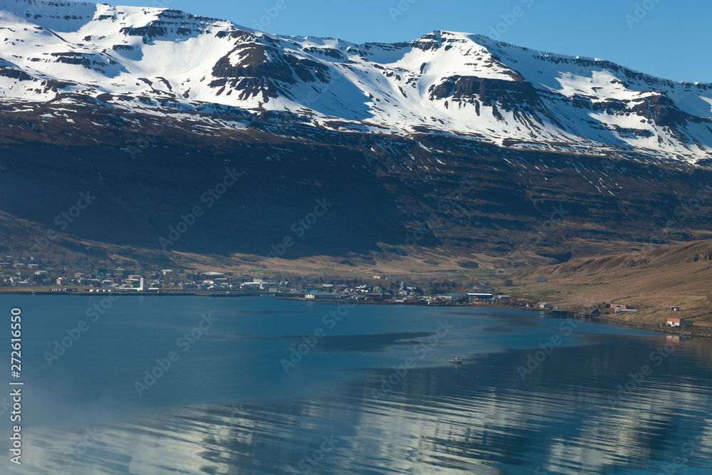 View to the small town and snowy mountains in the fjord of Iceland