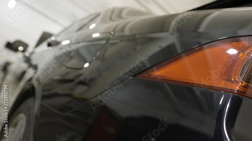Rear view of a black new car at the dealership, luxury concept. Art. Close up for red taillight and polished car wings, vehicle body details.