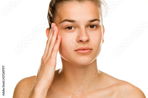 Young woman tightening  her face skin with the fingers on white background