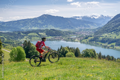 senior woman riding her electric mountain bike in springtimeon the mountains above the Alpsee near Immenstadt, Allgau,Bavaria, Germany
