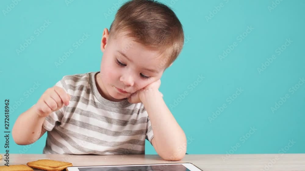 Young talented boy studying programs on the tablet, isolated on blue Young talented boy studying programs on the tablet, isolated on blue