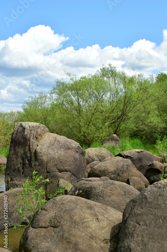 Sikachi Alyan on the Amur river. Basalt boulders. Blue sky with white clouds, green willow. Khabarovsk territory. Far East. Russia. 