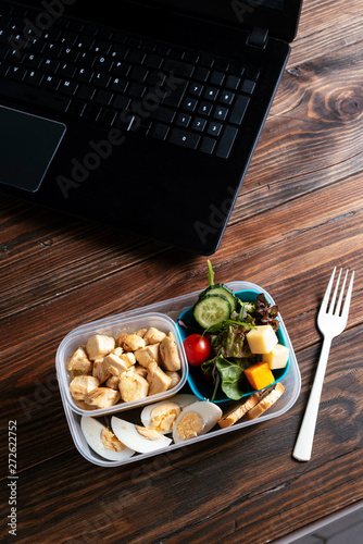Healthy food in lunch box on working table with laptop