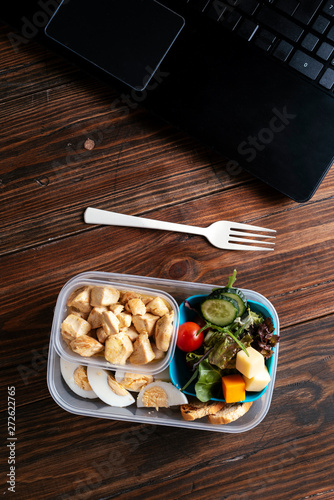 Healthy food in lunch box on working table with laptop