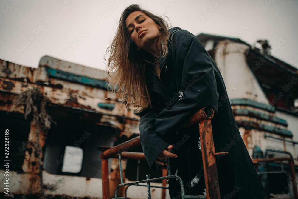 Young woman posing against the background of an old abandoned ship. Young woman posing against the background of an old abandoned ship.