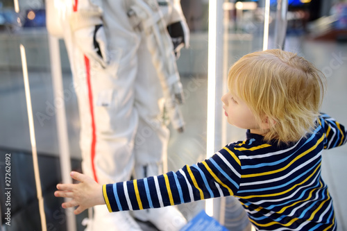 Little caucasian boy looking astronaut space suit in museum