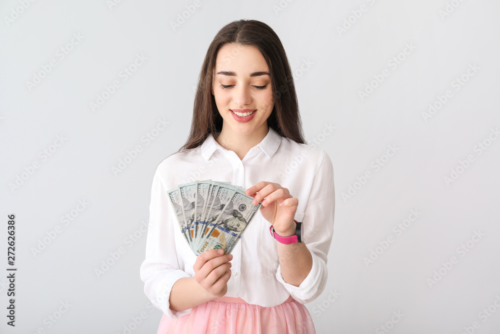Happy young woman with dollar banknotes on light background Happy young woman with dollar banknotes on light background