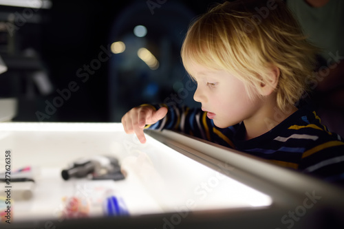 Fotografie Little сaucasian boy is looking an exposition in a scientific museum
