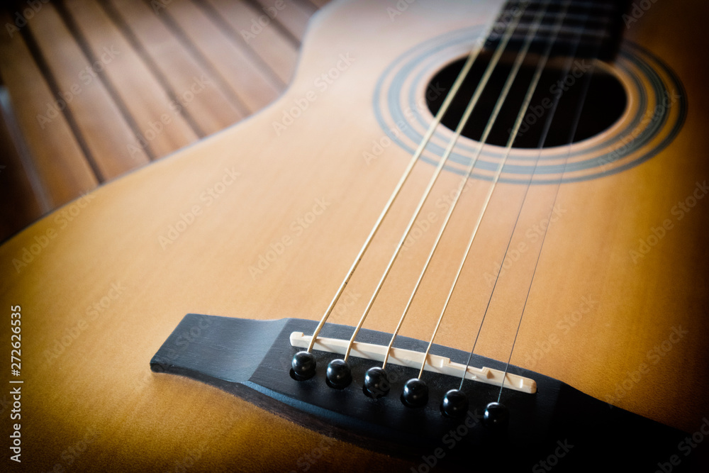 Fototapeta premium Acoustic guitar on a wooden background with copy space.The guitar is a fretted musical instrument that usually has six strings.