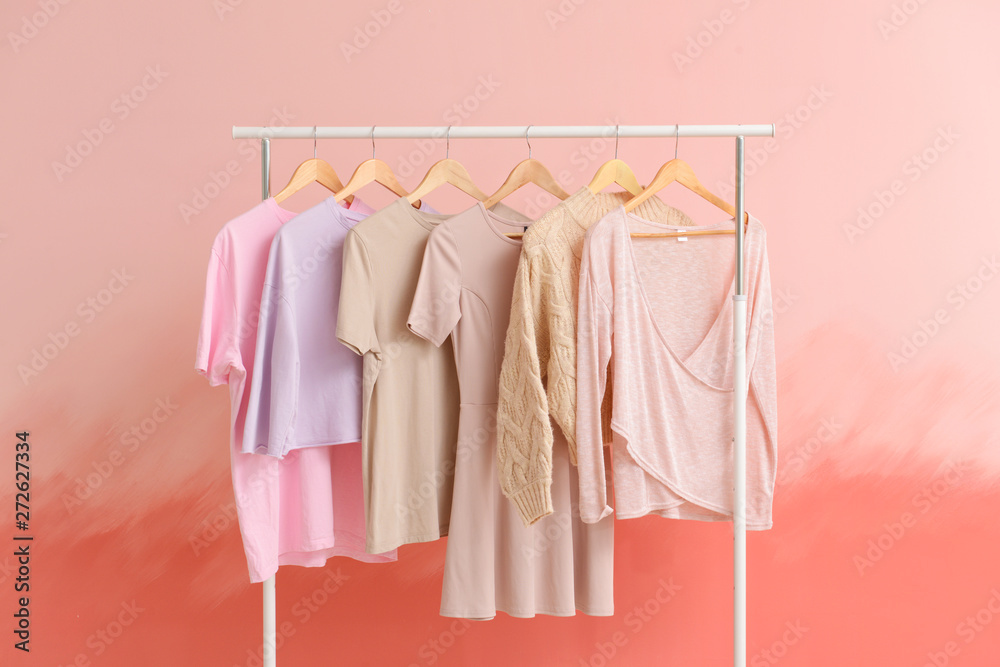 Rack with clothes after dry-cleaning on color background Stock Photo